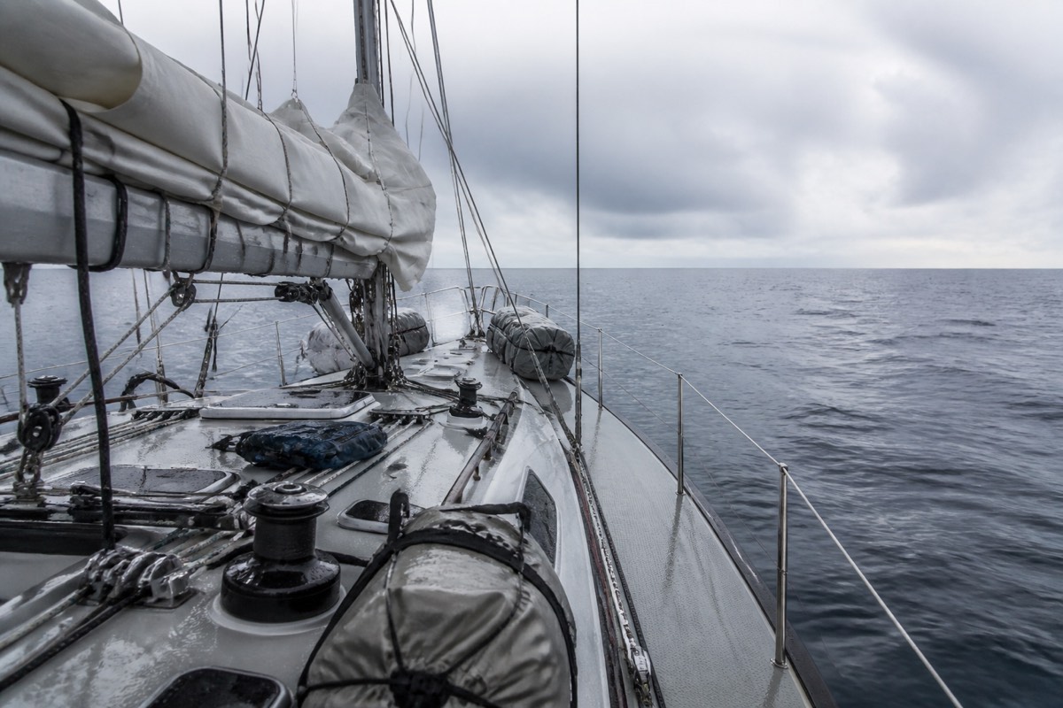 A reefed mainsail and secured deck gear on a gray offshore morning